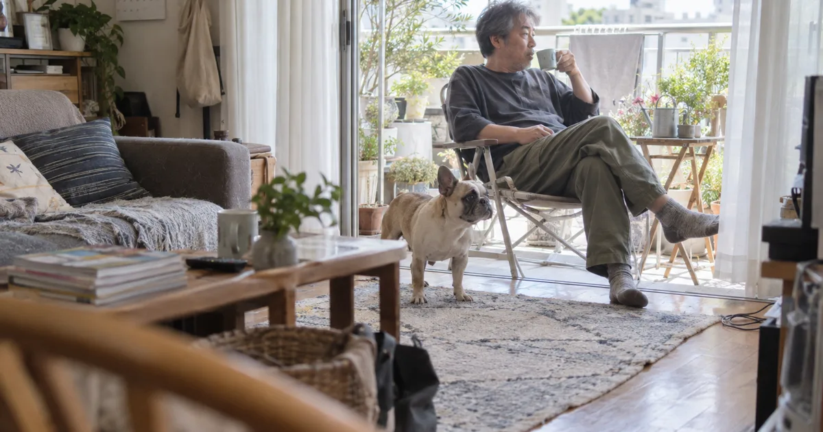 マンションのベランダでくつろぐ50代の男性とフレンチブルドッグ